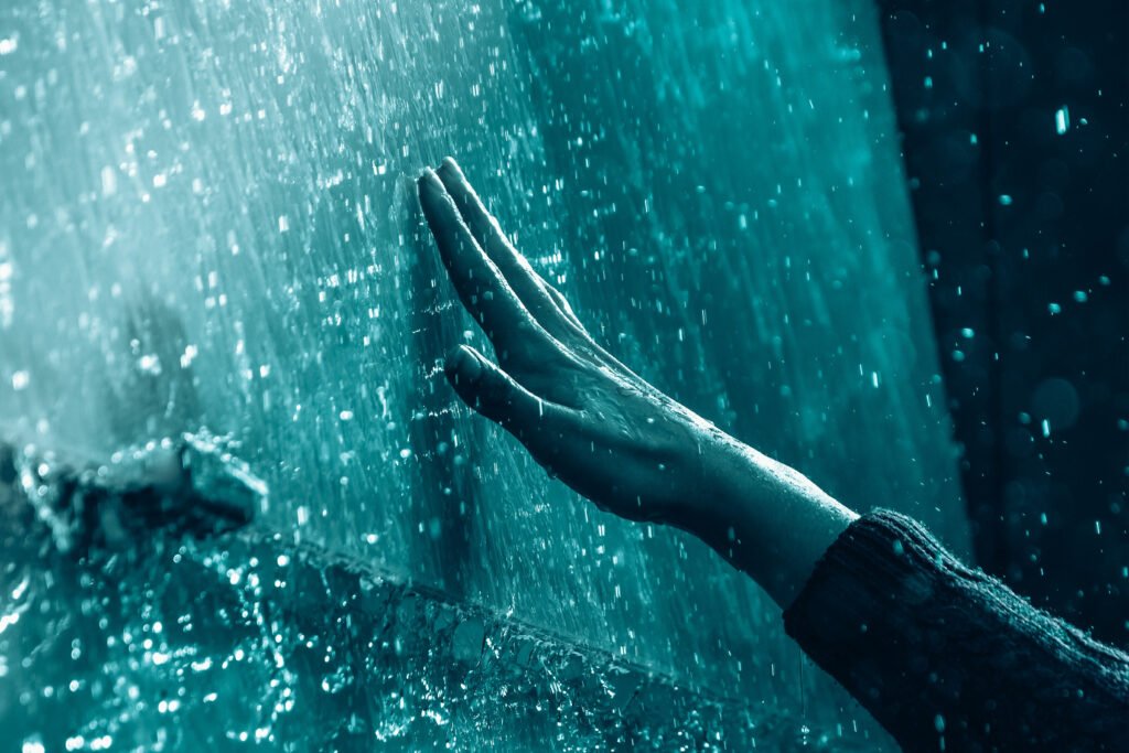 Person reaching their hand out to touch a wall of ice.