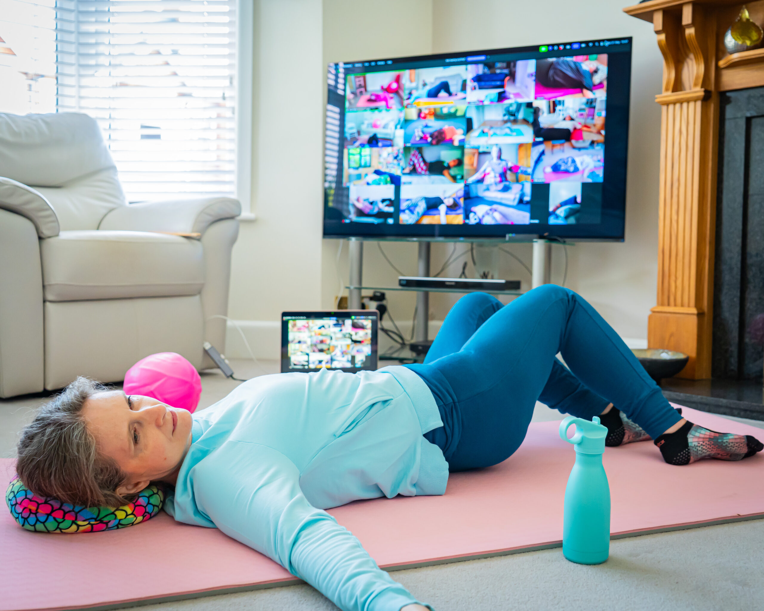 Mobilates member exercising on a mat while following an online class