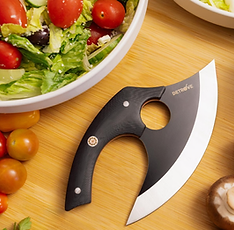 An Ulu knife, a curved blade with a handle, on a chopping board with vegetables